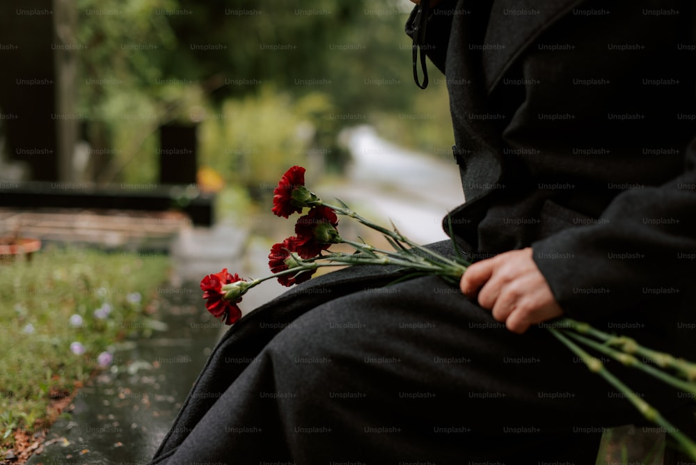 uma pessoa sentada em um banco com flores