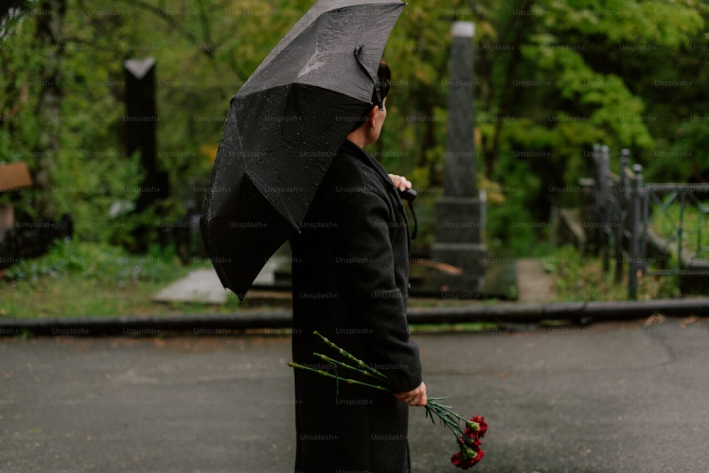 uma mulher em um casaco preto segurando um guarda-chuva preto