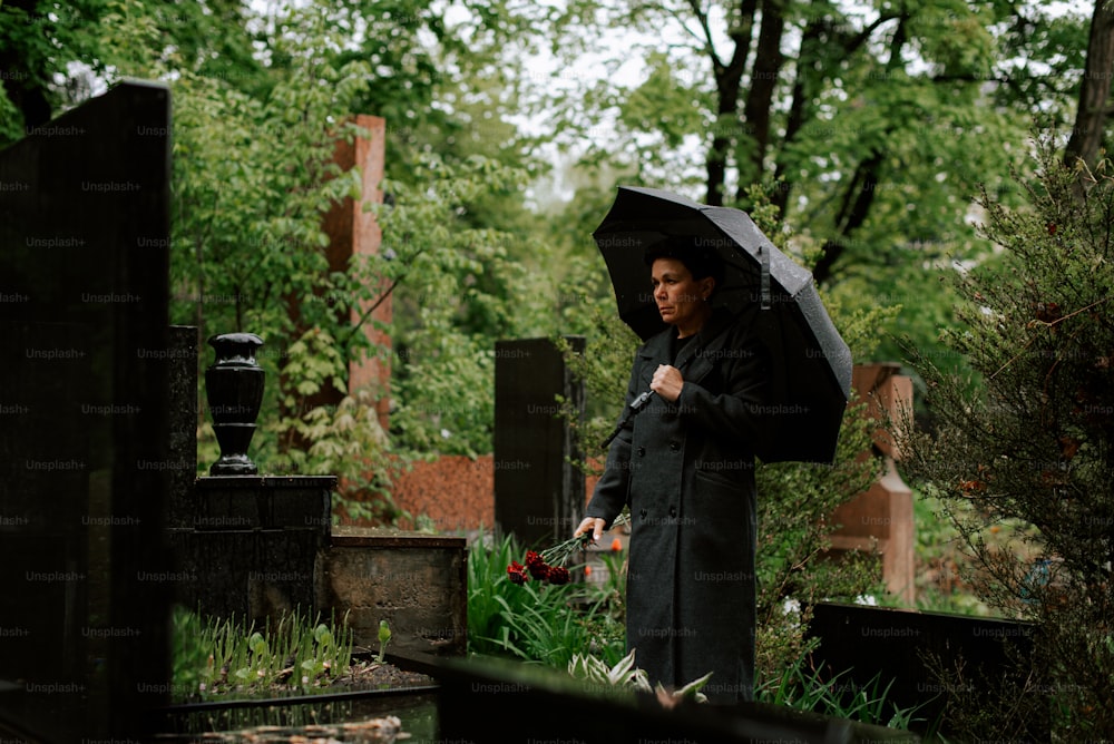 uma mulher segurando um guarda-chuva em um cemitério