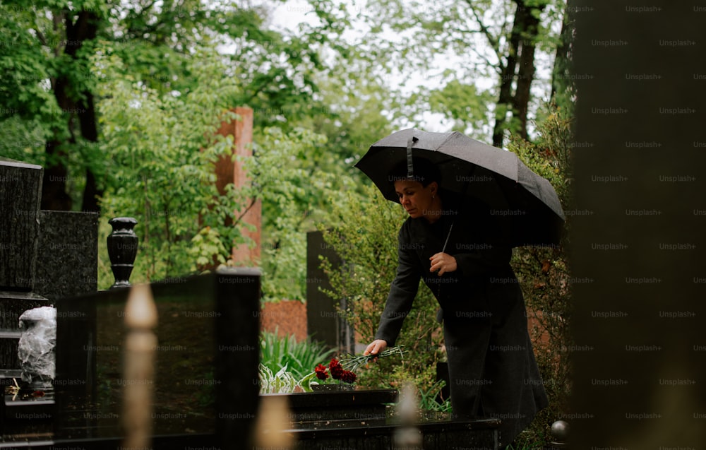 uma mulher segurando um guarda-chuva em um cemitério
