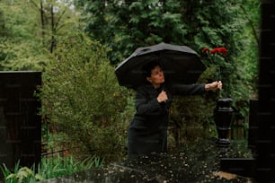 eine Frau, die einen schwarzen Regenschirm über dem Kopf hält