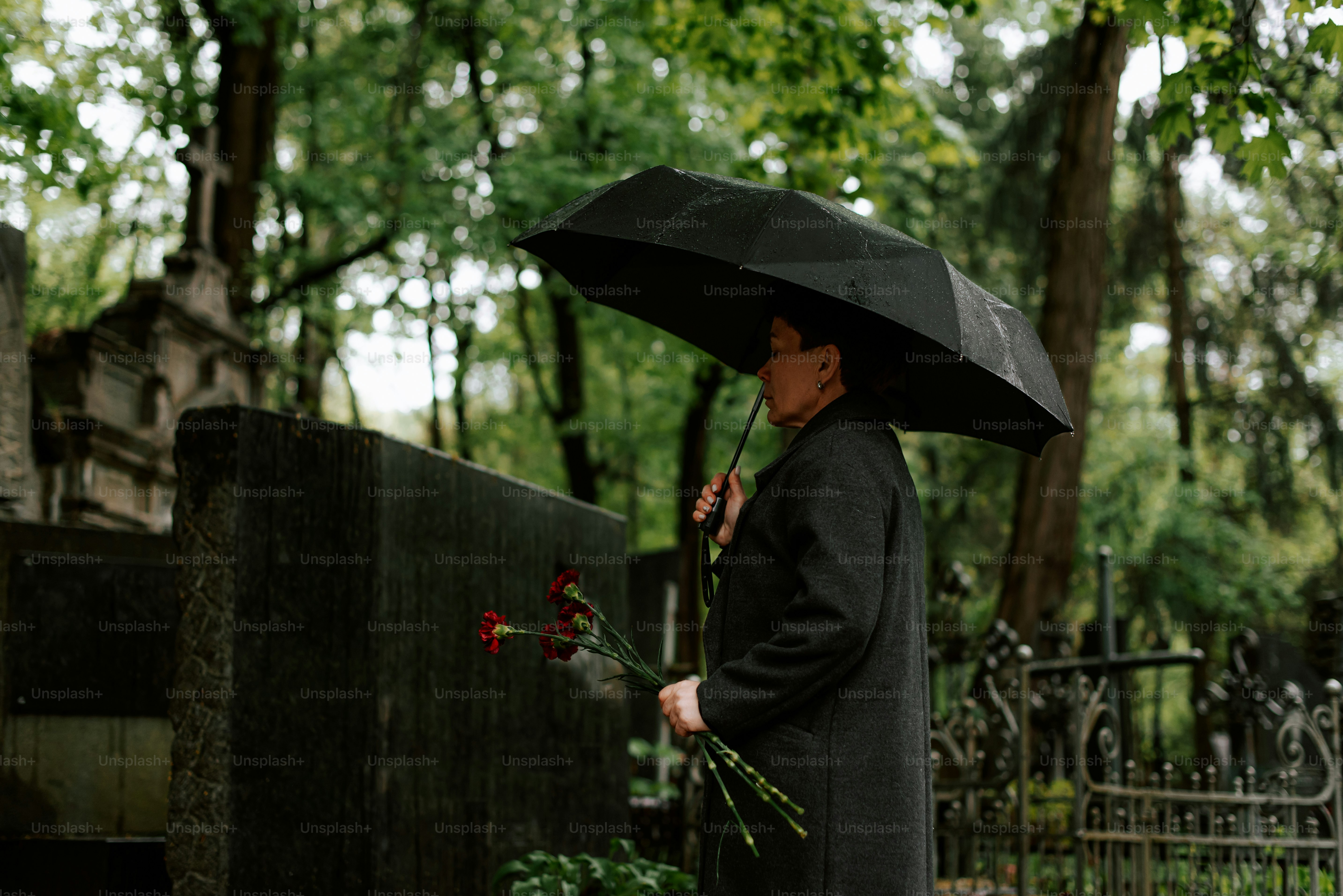 a woman in a black coat holding a black umbrella