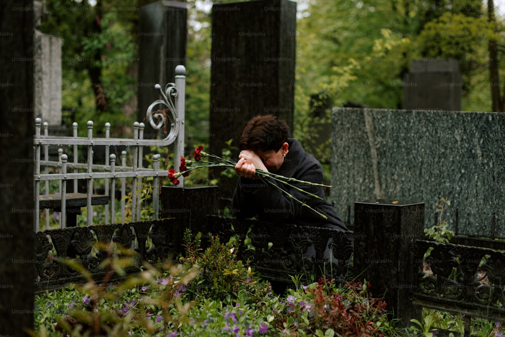 uma mulher sentada em um banco em um cemitério