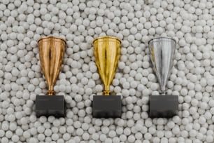 three trophies sitting on top of a pile of white balls