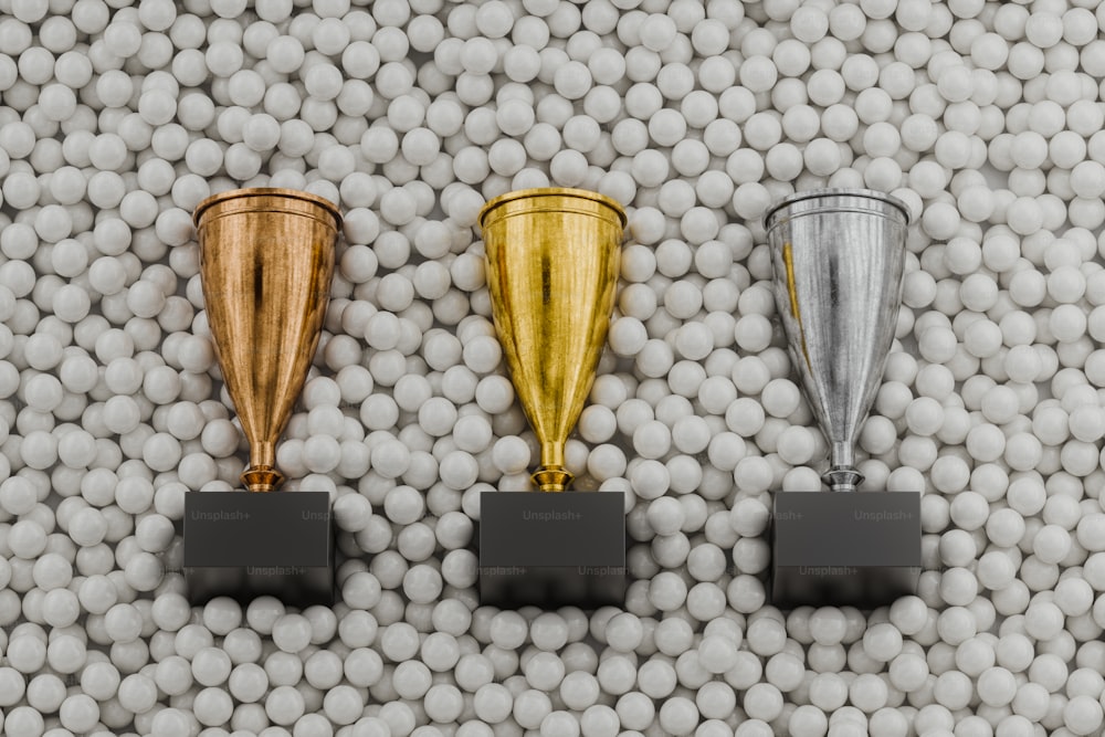 Tres trofeos colocados encima de una pila de bolas blancas