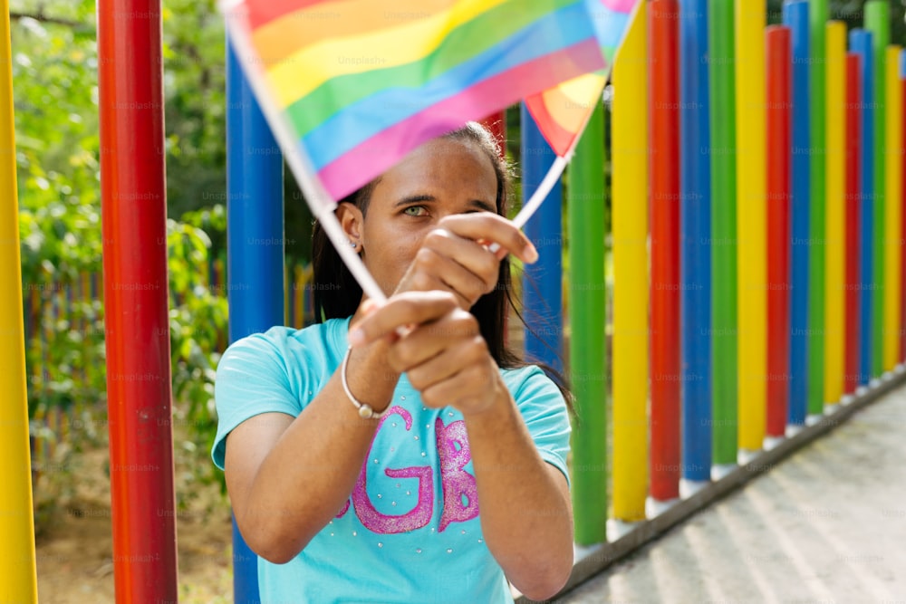 a woman holding a rainbow flag in front of a fence