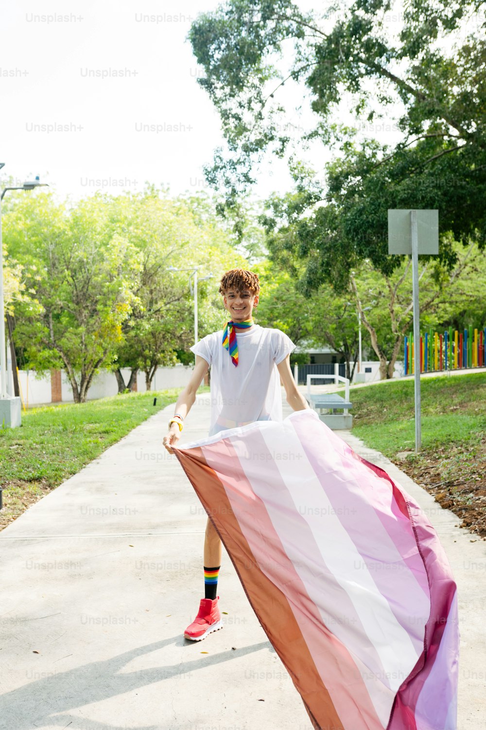 a young man holding a large rainbow colored flag