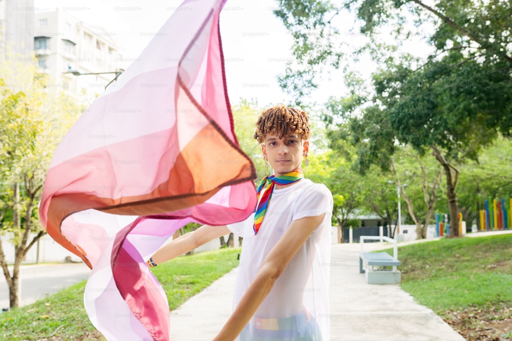 a young man holding a colorful scarf in a park