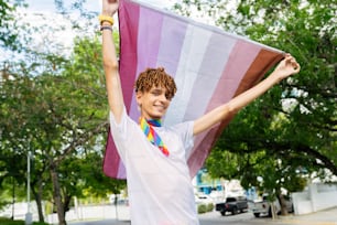 a young man holding a rainbow colored flag