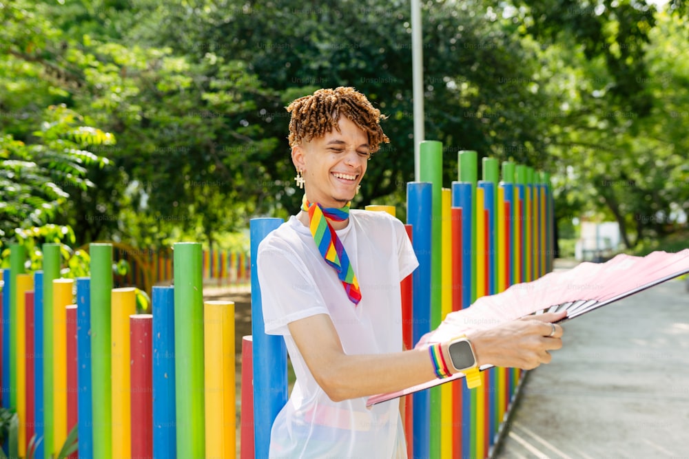 a woman holding a pink umbrella next to a colorful fence