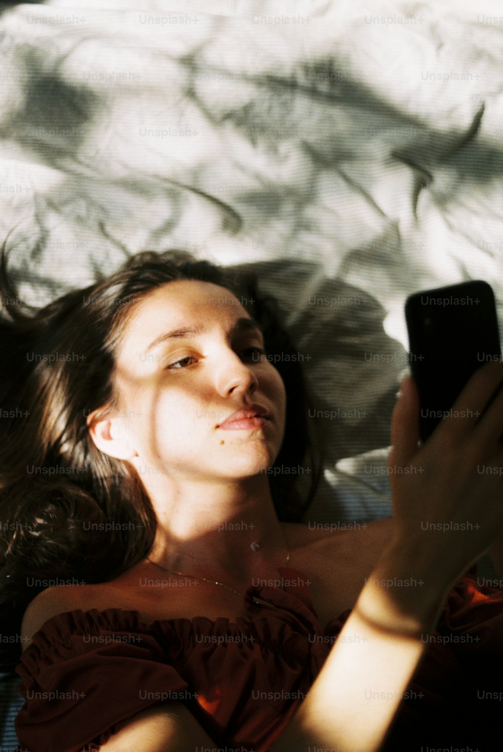 uma mulher deitada em uma cama segurando um telefone celular