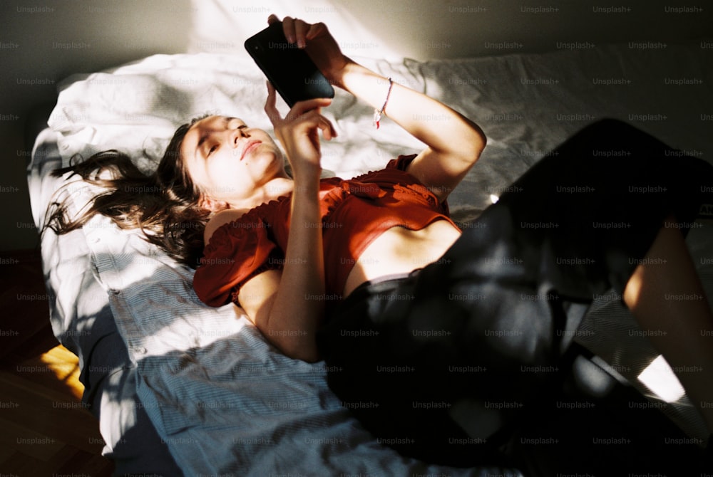 a woman laying on a bed holding a cell phone