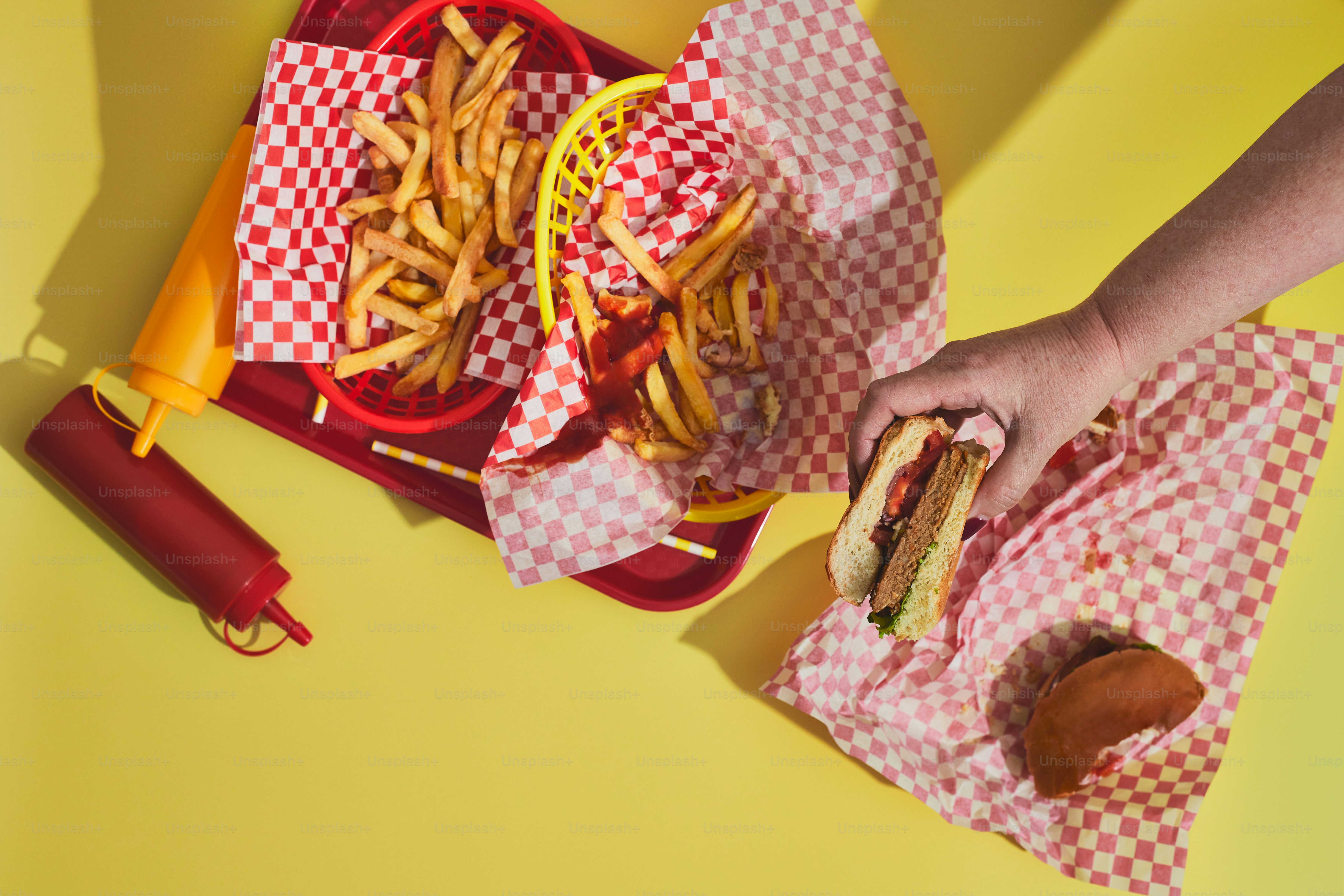 a person holding a sandwich and french fries