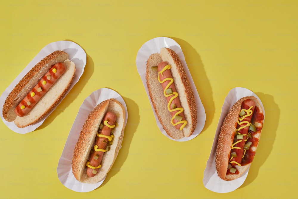 three hotdogs with mustard and ketchup on paper plates