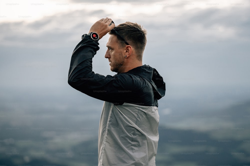 a man standing on top of a mountain with his hands on his head