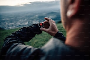 Un homme regardant sa montre alors qu’il se tient au sommet d’une colline