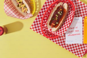 a couple of hot dogs sitting on top of a red and white checkered paper