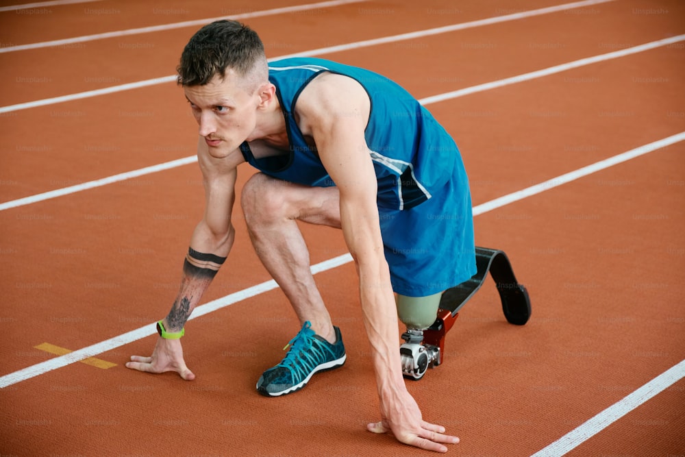 a man kneeling down on a track with a tennis racquet