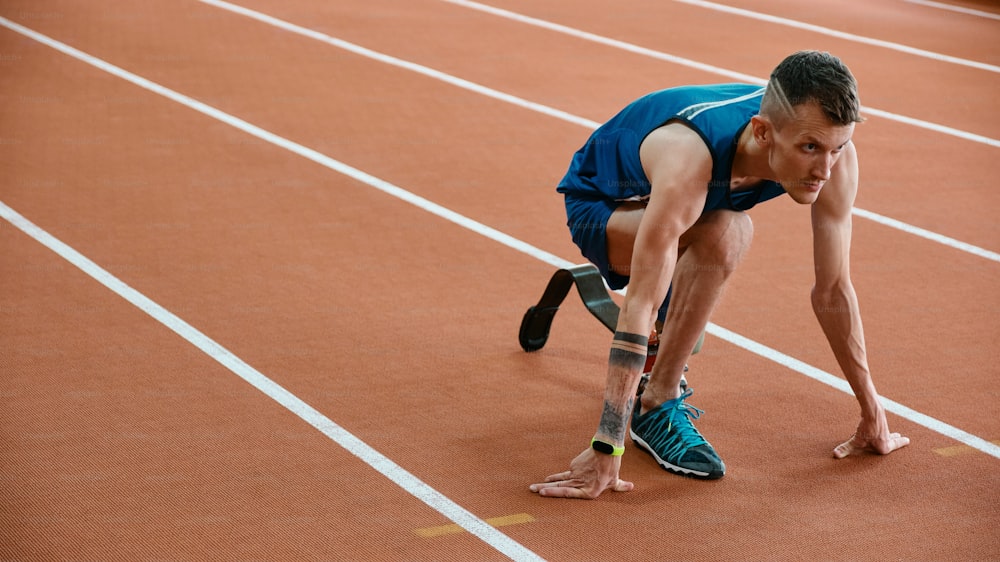 a man in a blue shirt is on a track with a tennis racket