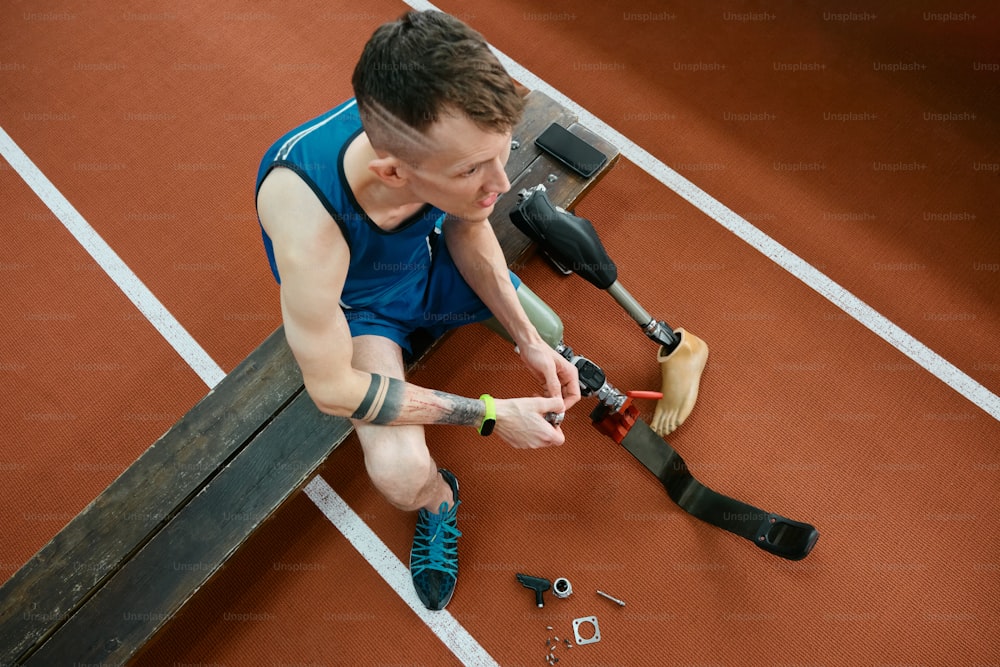 a man sitting on a tennis court holding a tennis racquet