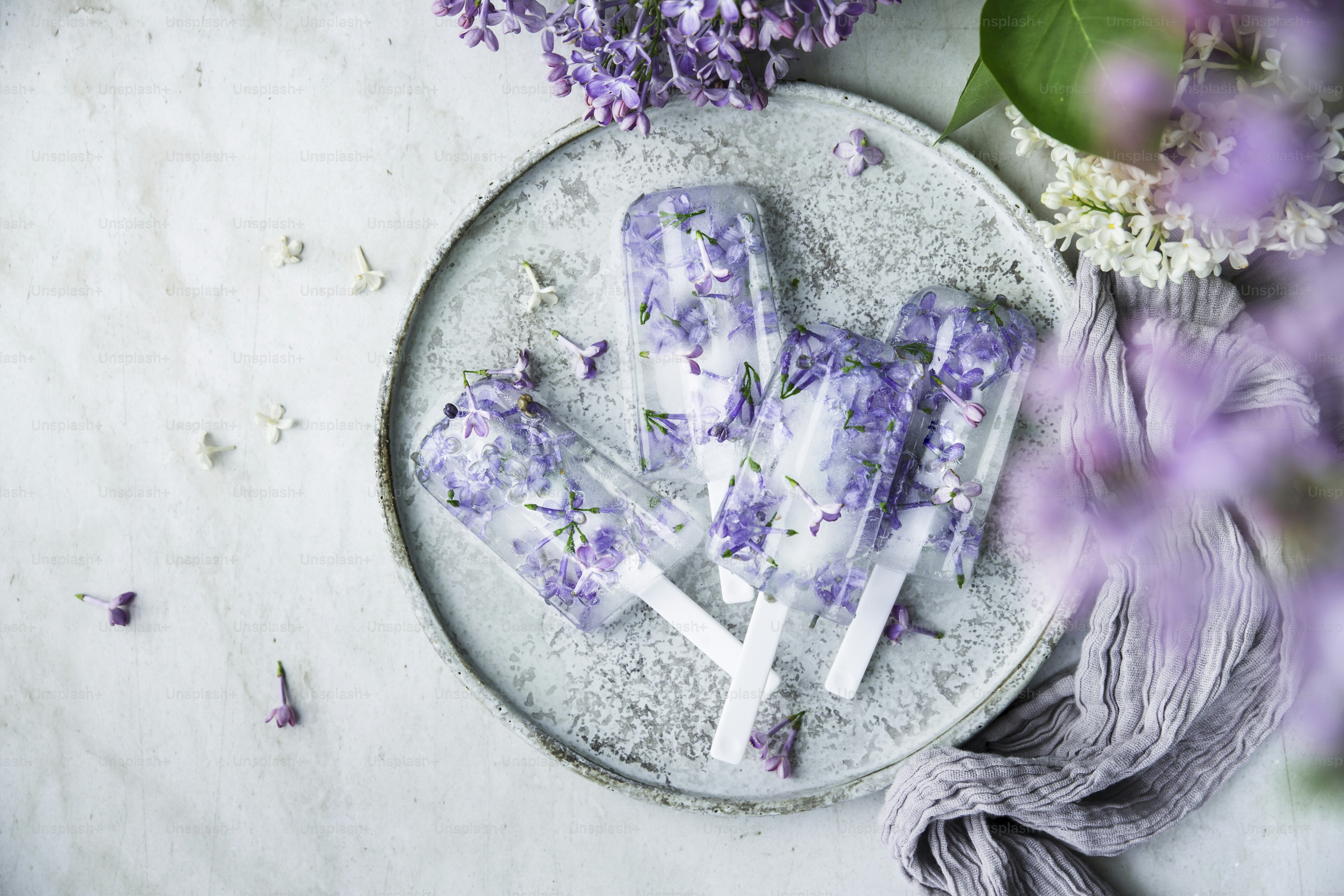 a white plate topped with purple flowers next to purple flowers