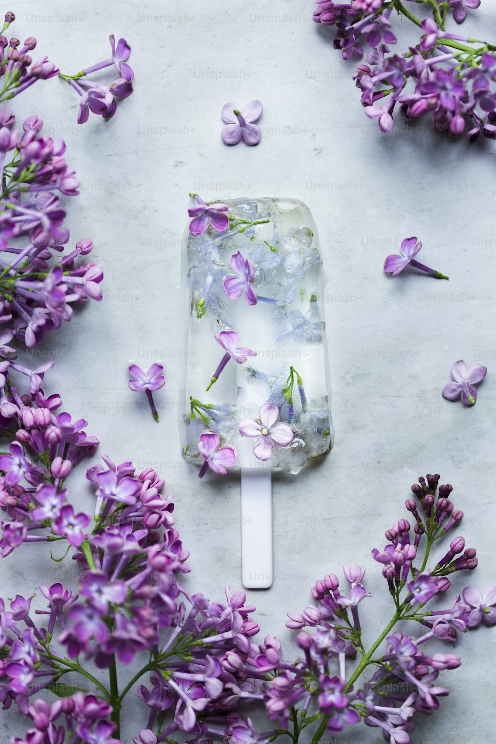 a popsicle filled with purple flowers on top of a table