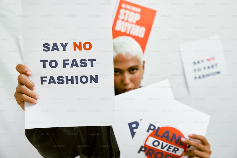 uma pessoa segurando uma placa que diz não ao fast fashion