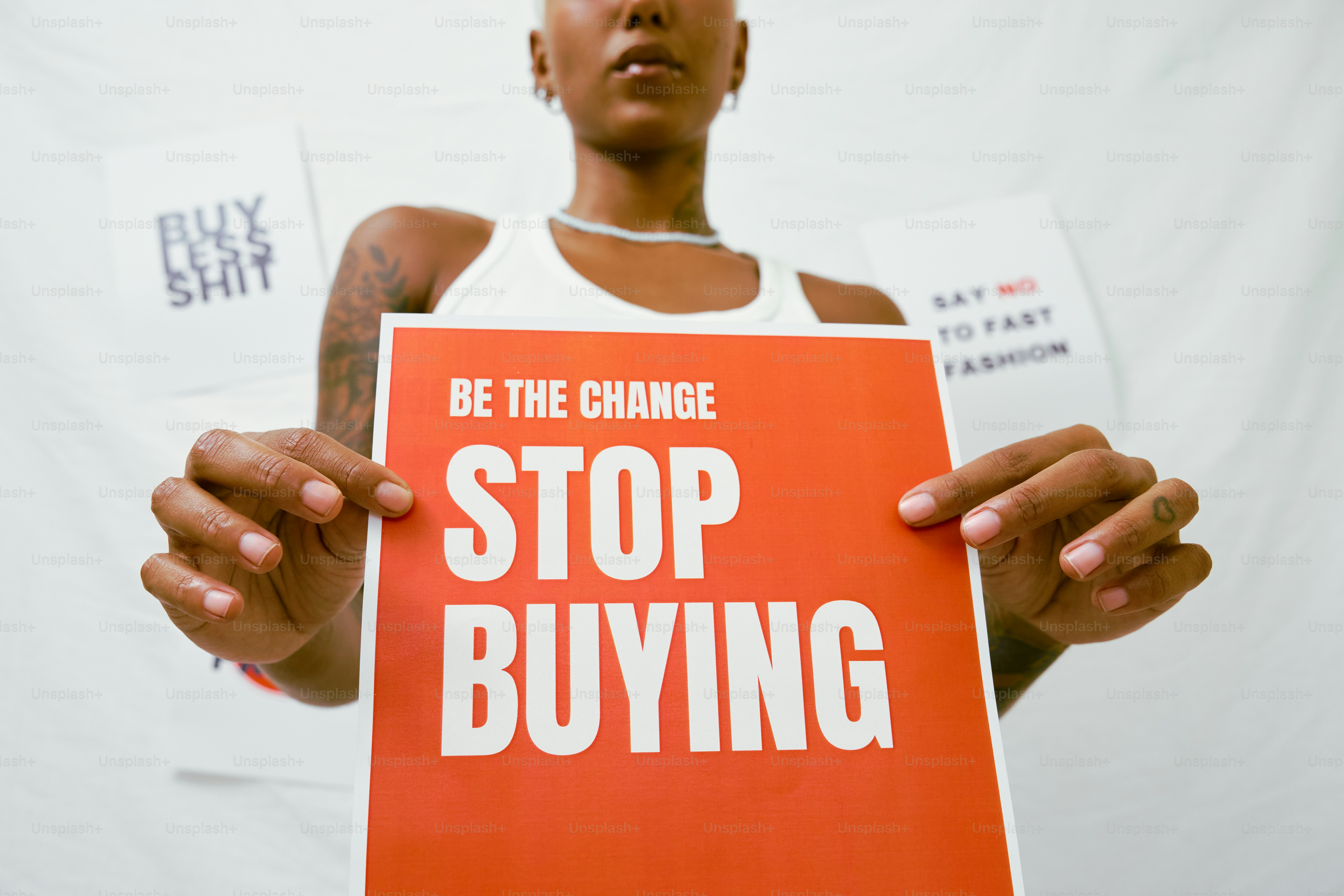 A woman holding a sign that says be the change stop buying photo ...