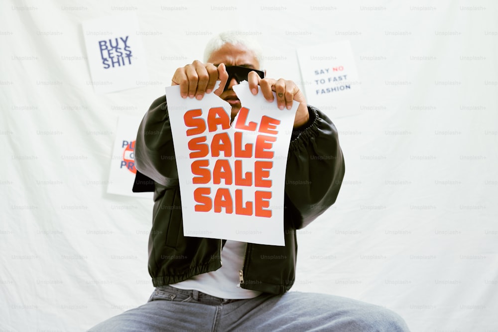 a man holding a sale sign in front of his face