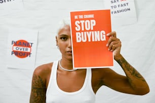 a woman holding up a sign that says stop buying