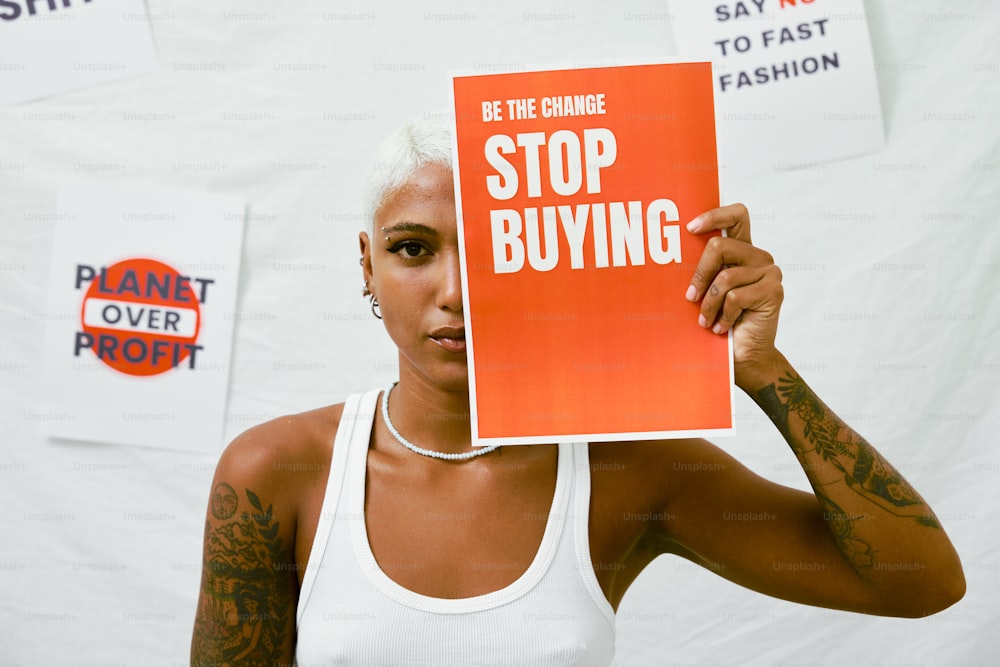 una donna che tiene in mano un cartello che dice di smettere di comprare