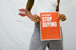 a person holding a sign that says stop buying