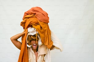 a man is holding a pile of clothes on his head