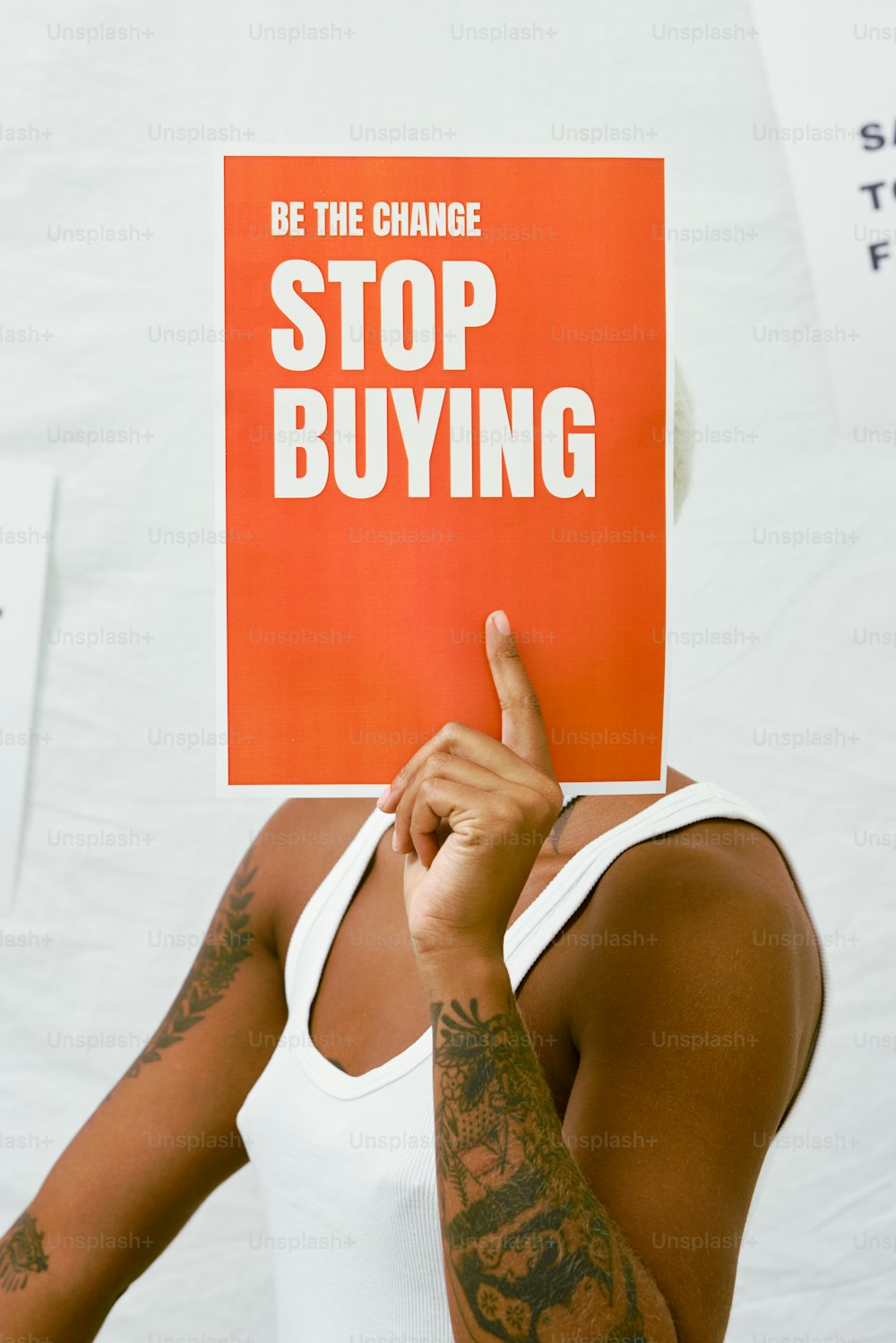 una mujer sosteniendo un cartel que dice Sé el cambio, deja de comprar