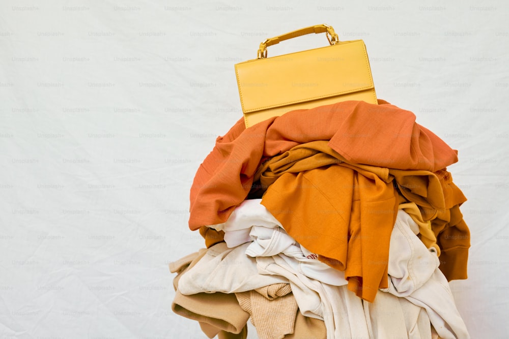 uma mala amarela sentada em cima de uma pilha de roupas