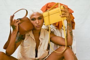 a woman sitting on the ground holding a yellow purse