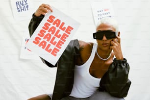 una donna che tiene in mano un cartello di vendita e un paio di occhiali da sole