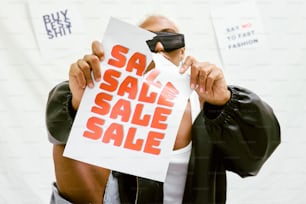 a man holding up a sign with a sale sale on it