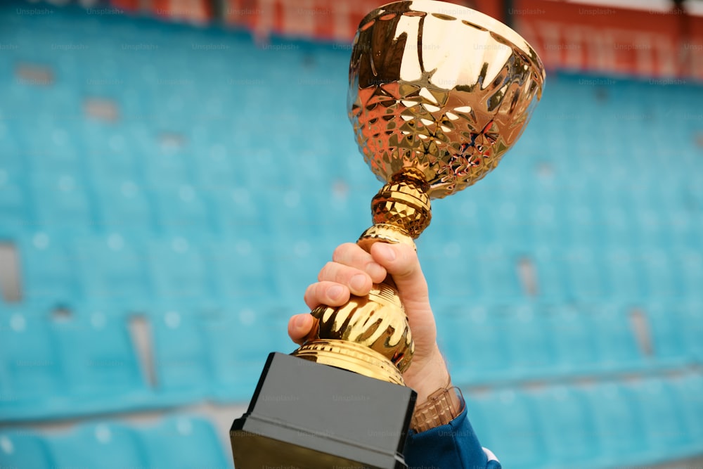 a person holding up a trophy in front of a stadium