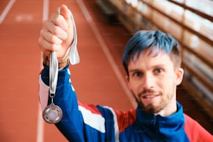 um homem de cabelos azuis segurando uma medalha