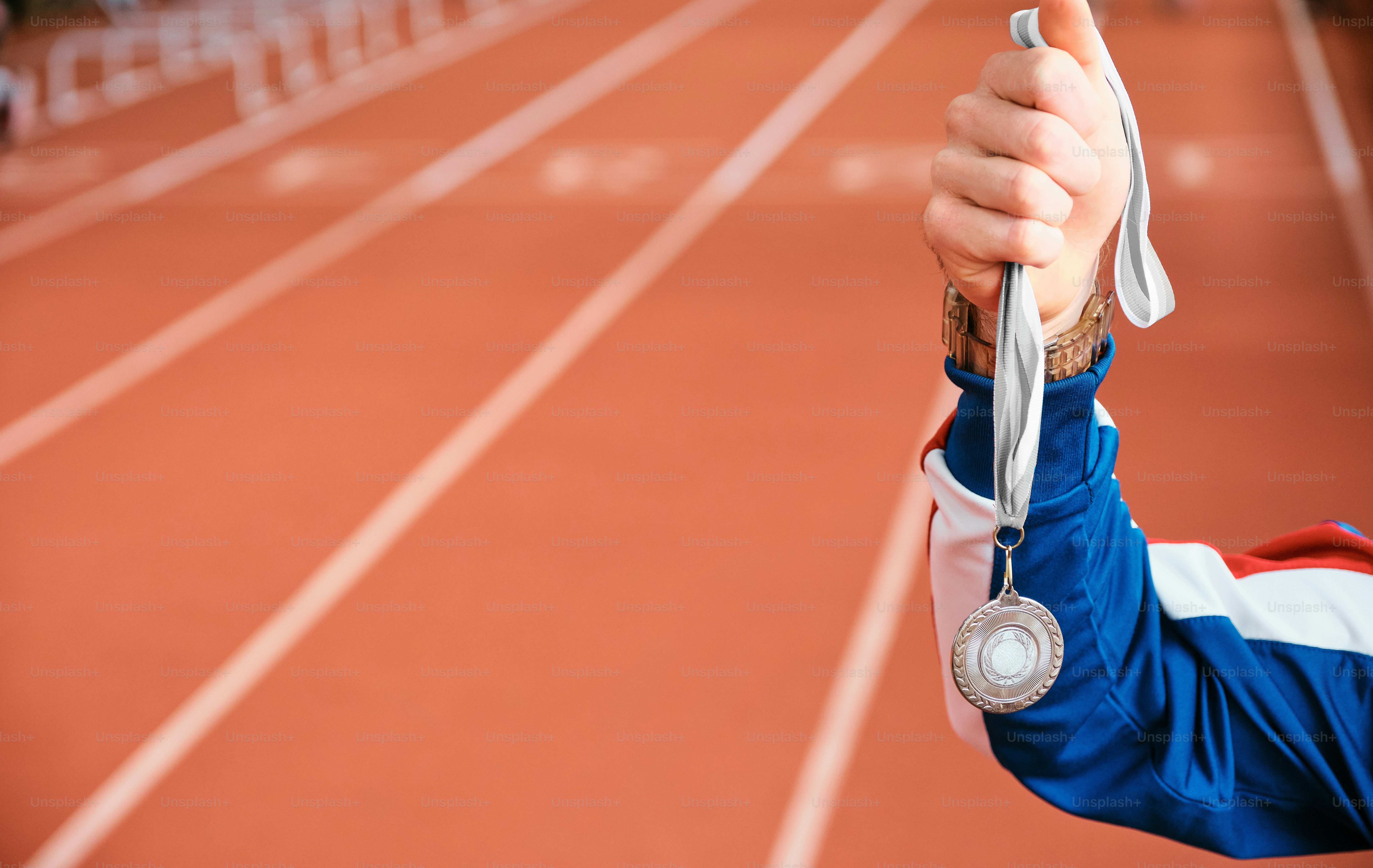 a person holding up a medal on a track