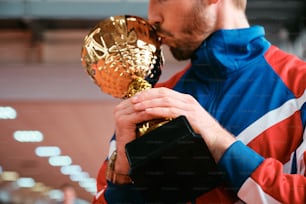 un hombre besando un trofeo de oro en una habitación
