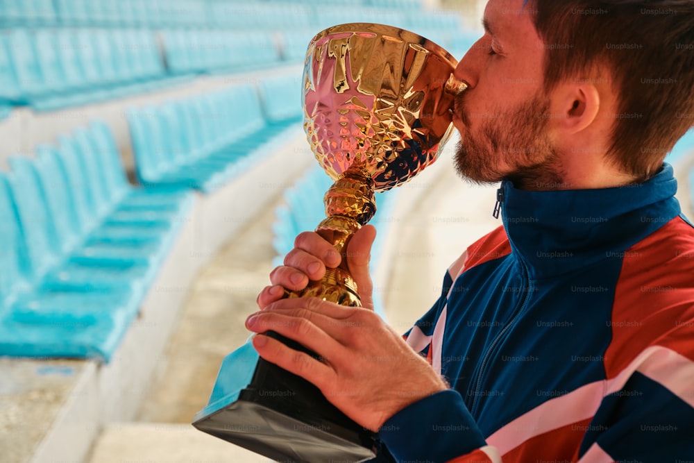 a man kissing a trophy in a stadium