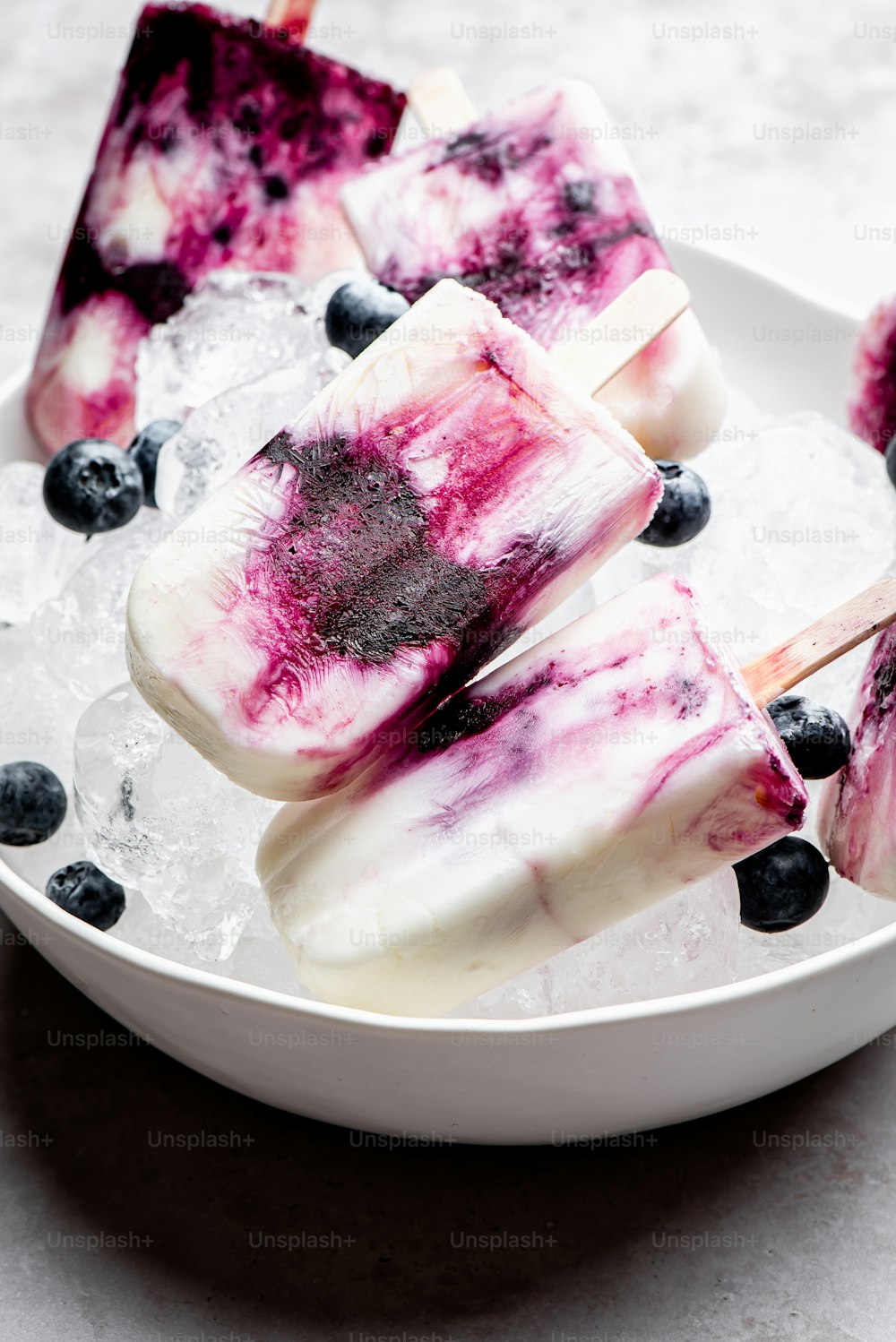 a white bowl filled with blueberry popsicles