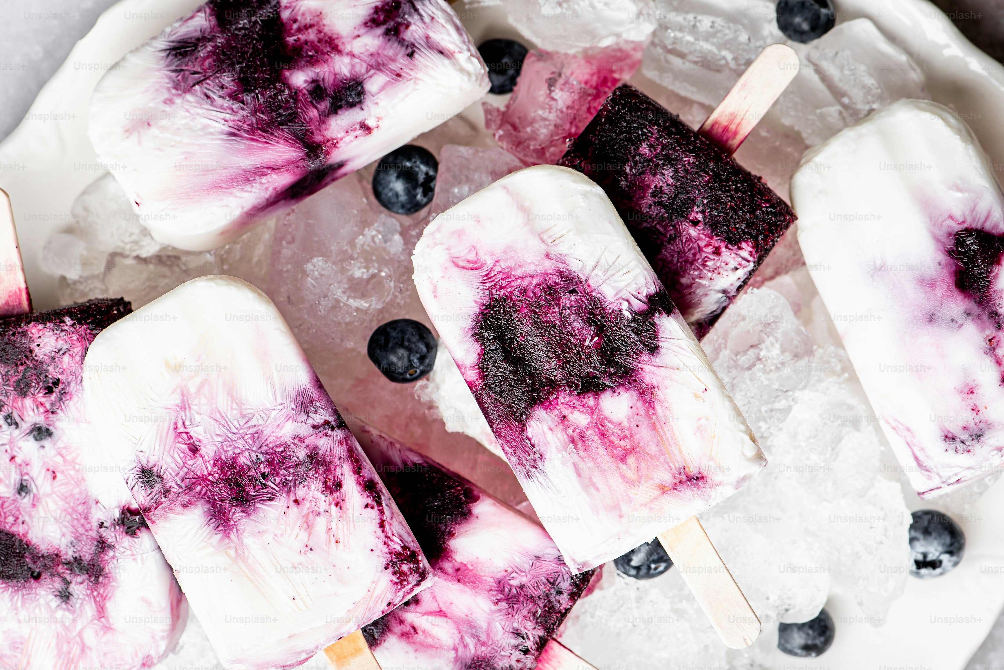 a white plate topped with popsicles covered in blueberries