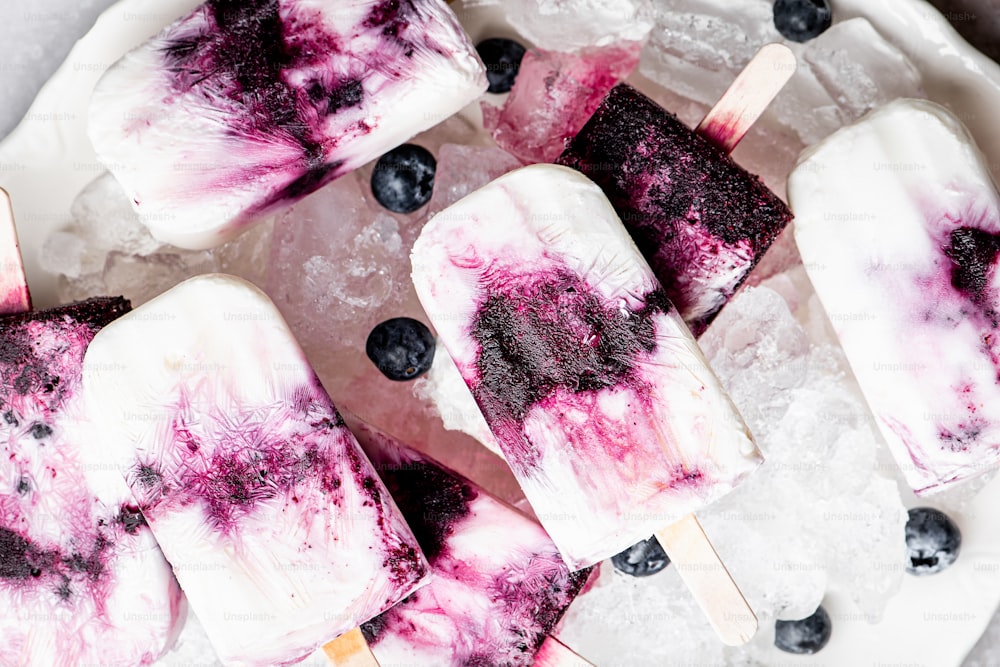 a white plate topped with popsicles covered in blueberries