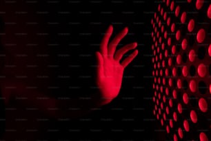 Die Hand einer Person, die eine Wand mit roten Lichtern berührt