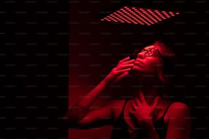 uma mulher em um quarto escuro com uma luz vermelha