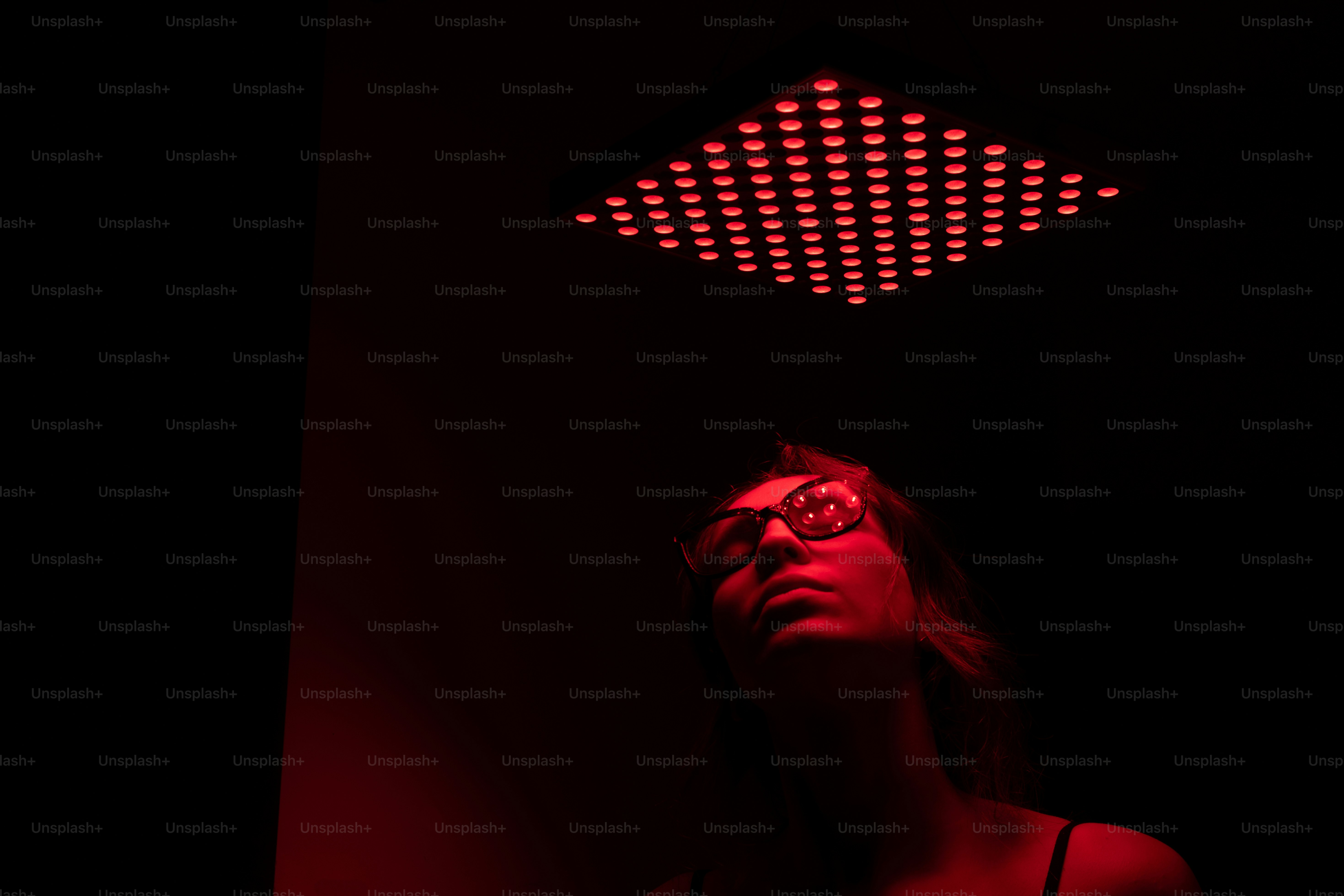 a woman in a dark room with a red light above her head