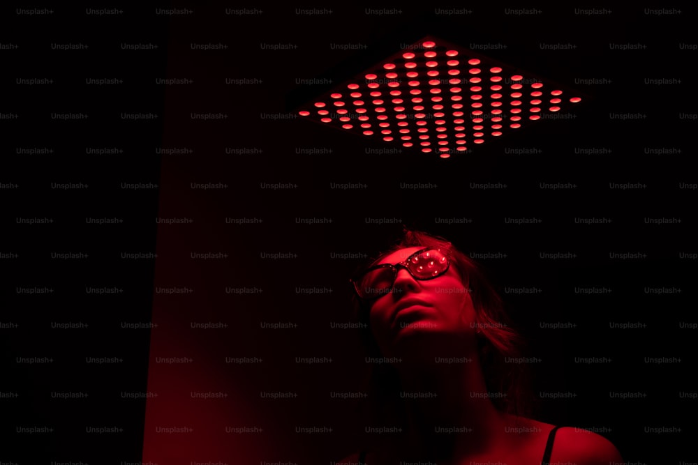 a woman in a dark room with a red light above her head